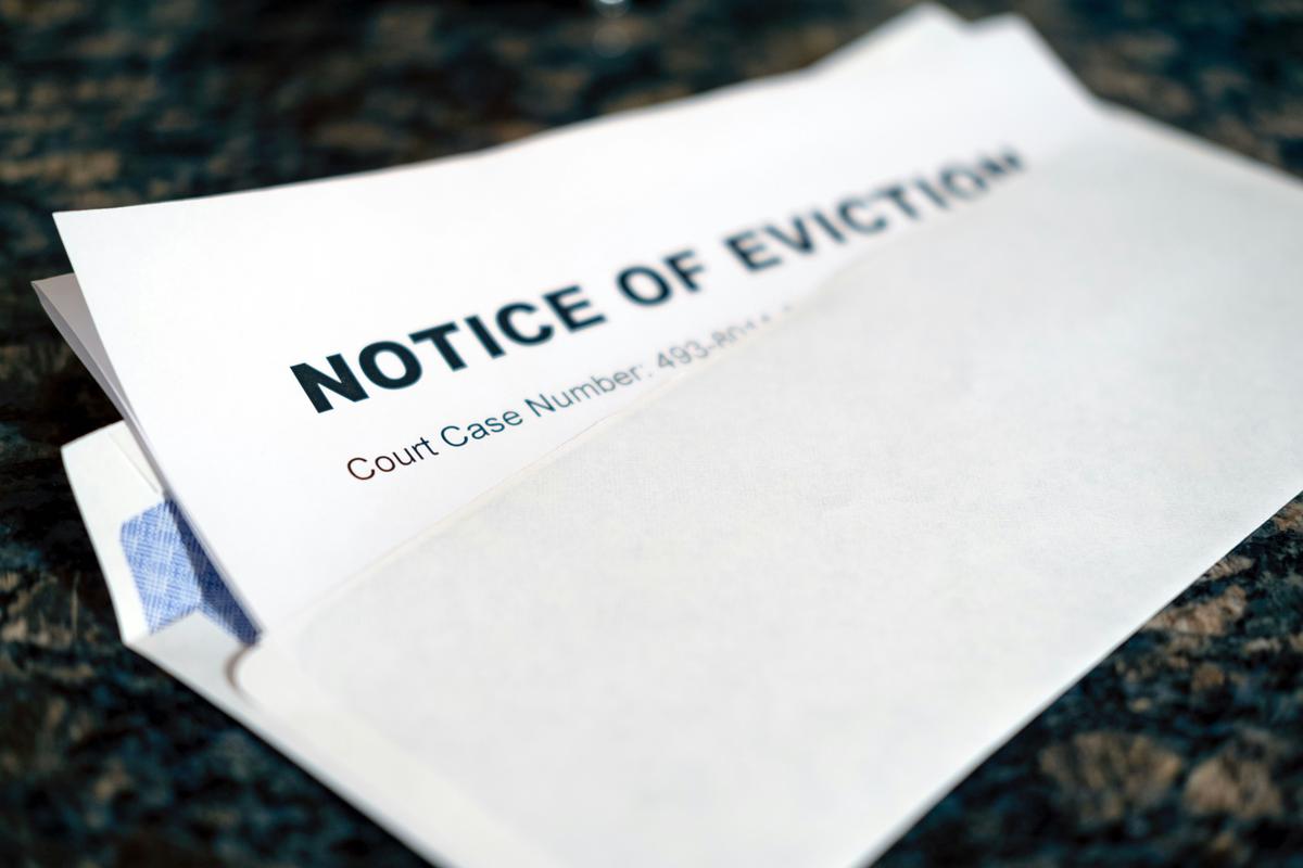 An image of a tenant reclaiming personal belongings after an eviction, with a landlord watching. The tenant is holding a small box and looking relieved, while the landlord looks frustrated. The setting is a hallway with apartment doors in the background.