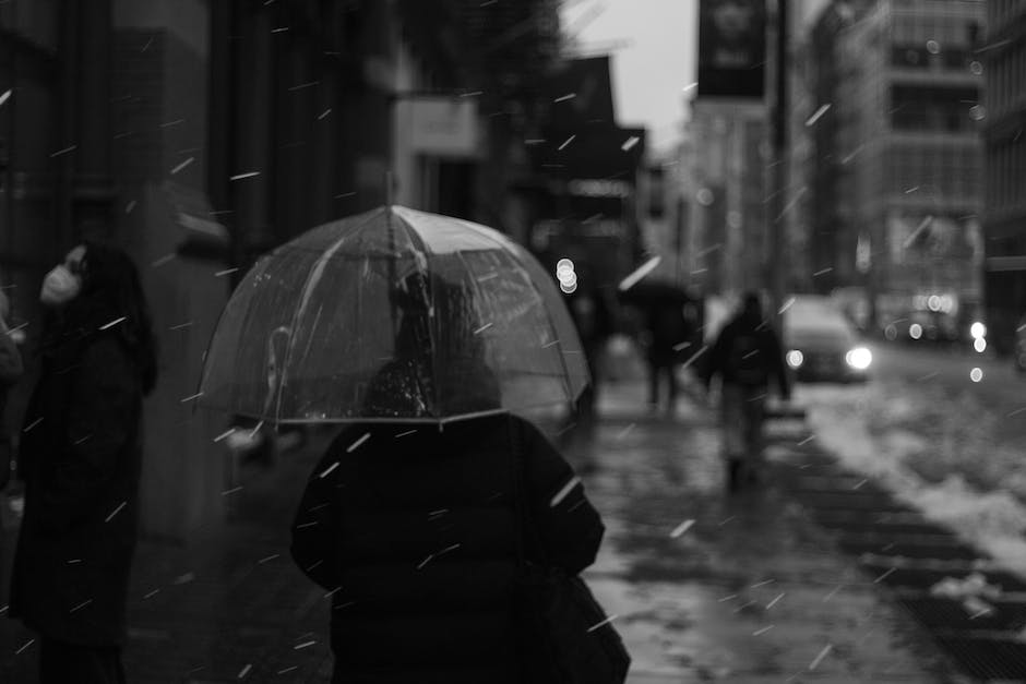 Image of a person holding an umbrella protecting a house, representing the need for renters insurance